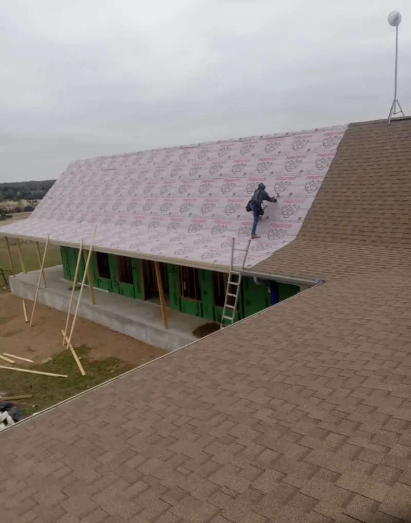 Worker preparing underlayment for a metal roof installation in Oxford